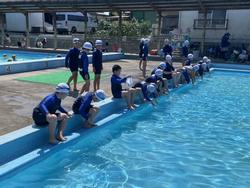 プールサイドに座り、水を体に3年生