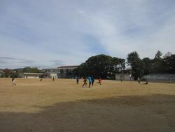 秋空のもと運動場で遊ぶ子どもたち