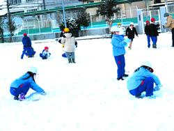運動場で雪遊びをする三樹っ子たち